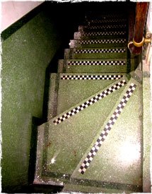 The staircase is lined with two tone green terrazzo with black and white nosings.